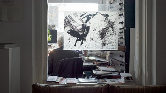 Gunar Barthel in seiner Berliner Wohnungsgalerie (Im Rücken ein Sprachblatt vom 5. Mosch Carlfriedrich Claus) in "Go Clara Go: die Kunst des kreativen Widerstands" (2025)