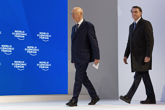 Klaus Schwab, Gründer und Geschäftsführender Vorsitzender des Weltwirtschaftsforums, Jair Bolsonaro, Präsident von Brasilien (v.l.n.r.) während Bolsonaros Rede beim Jahrestreffen des Weltwirtschaftsforums im Congress Centre in Davos am 22. Januar 2018 ("Das Forum", 2019); 