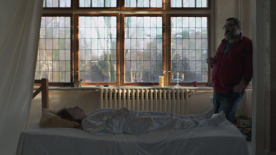 Brigitte Böttrich (liegend), Heiko Pinkowski in "Auf und Ableben" (2019); Quelle: Filmfestival Max Ophüls Preis 2020, © Auf und Ableben GbR