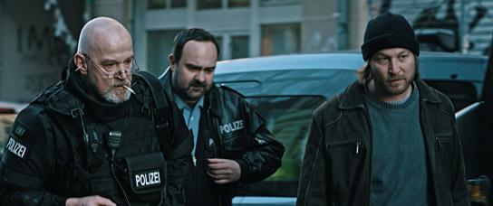 Tom Keune (mitte), Thilo Prothmann (rechts) in "Der letzte Mieter" (2018); Quelle: Dualfilm Verleih, DFF, © Dualfilm GmbH